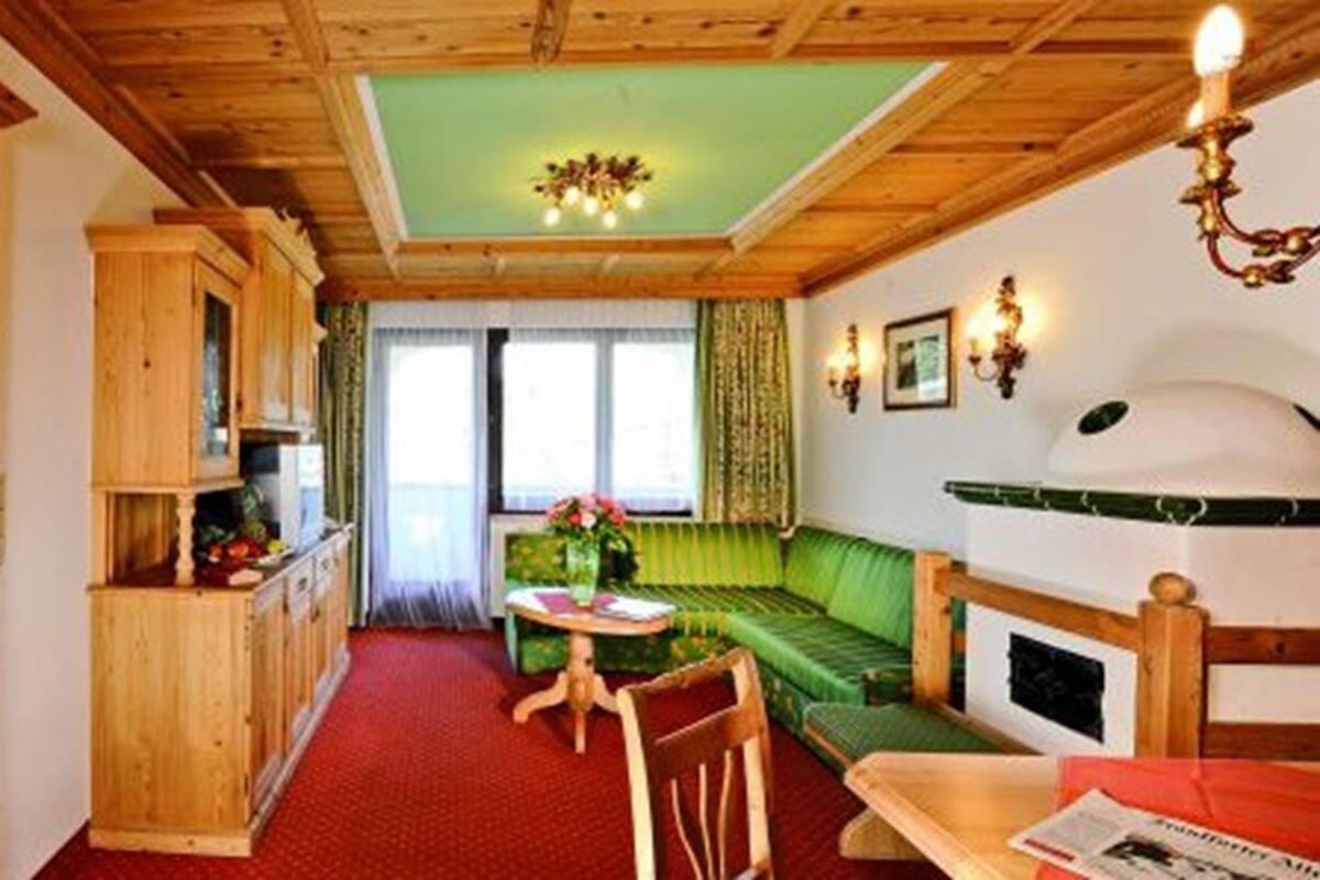 Une pièce chaleureuse avec un lit, une armoire en bois, un canapé vert, une petite table et une cheminée.