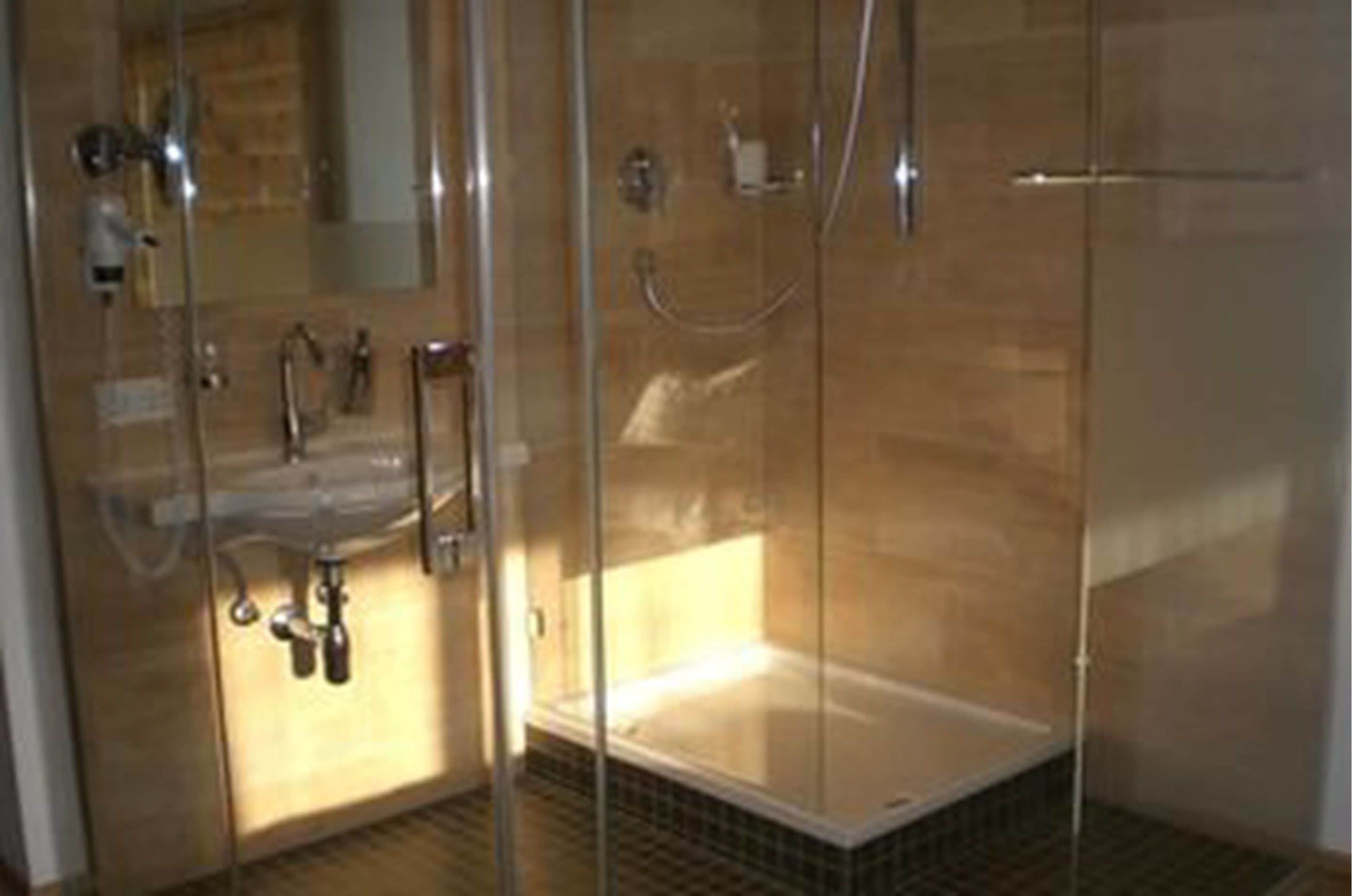 A glass-enclosed shower area with a bathtub, a sink, and a mirror.