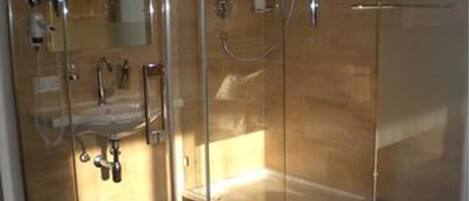 A glass-enclosed shower area with a bathtub, a sink, and a mirror.