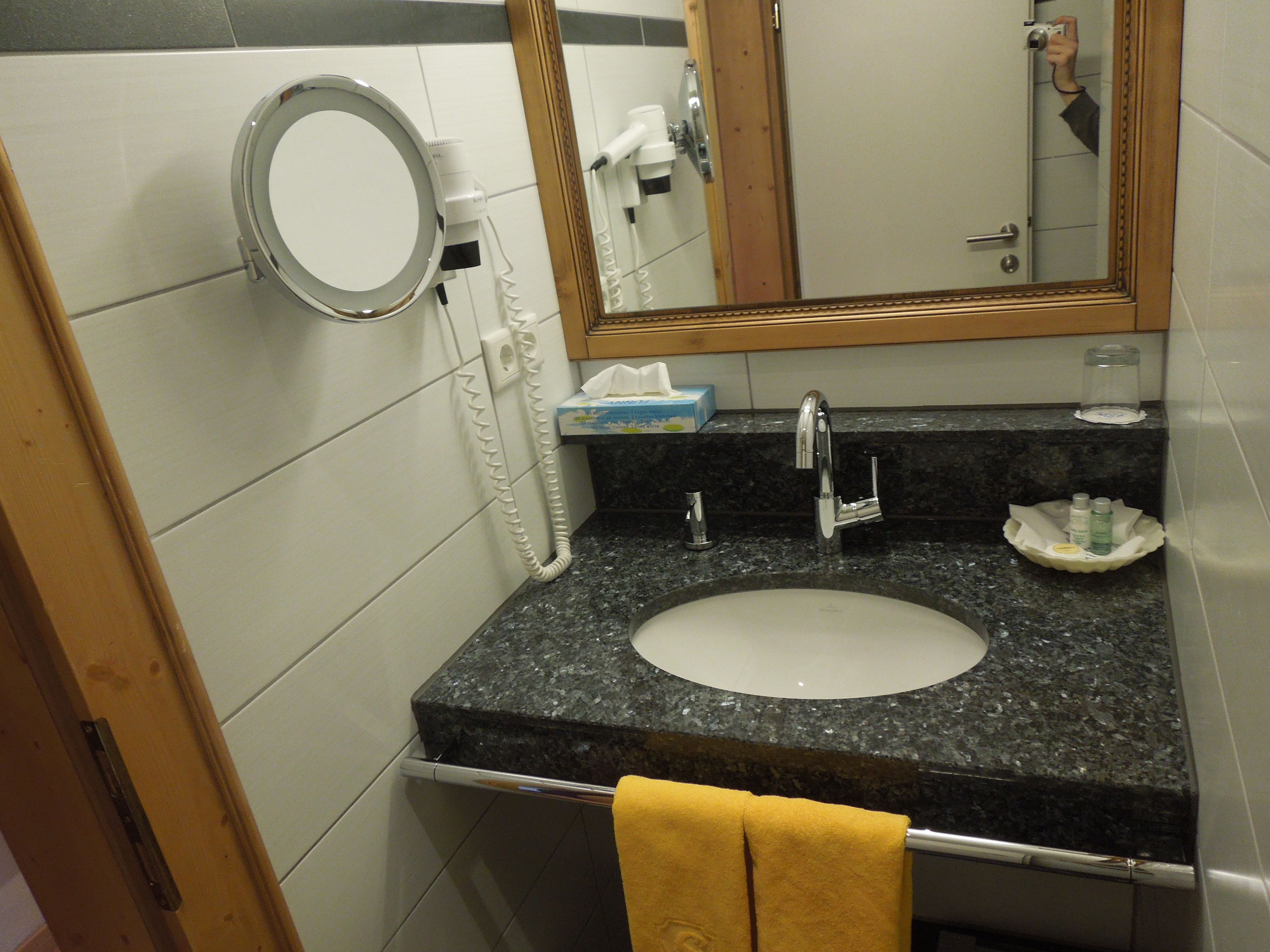 Un baño con lavamanos, espejo y perchero para toallas.