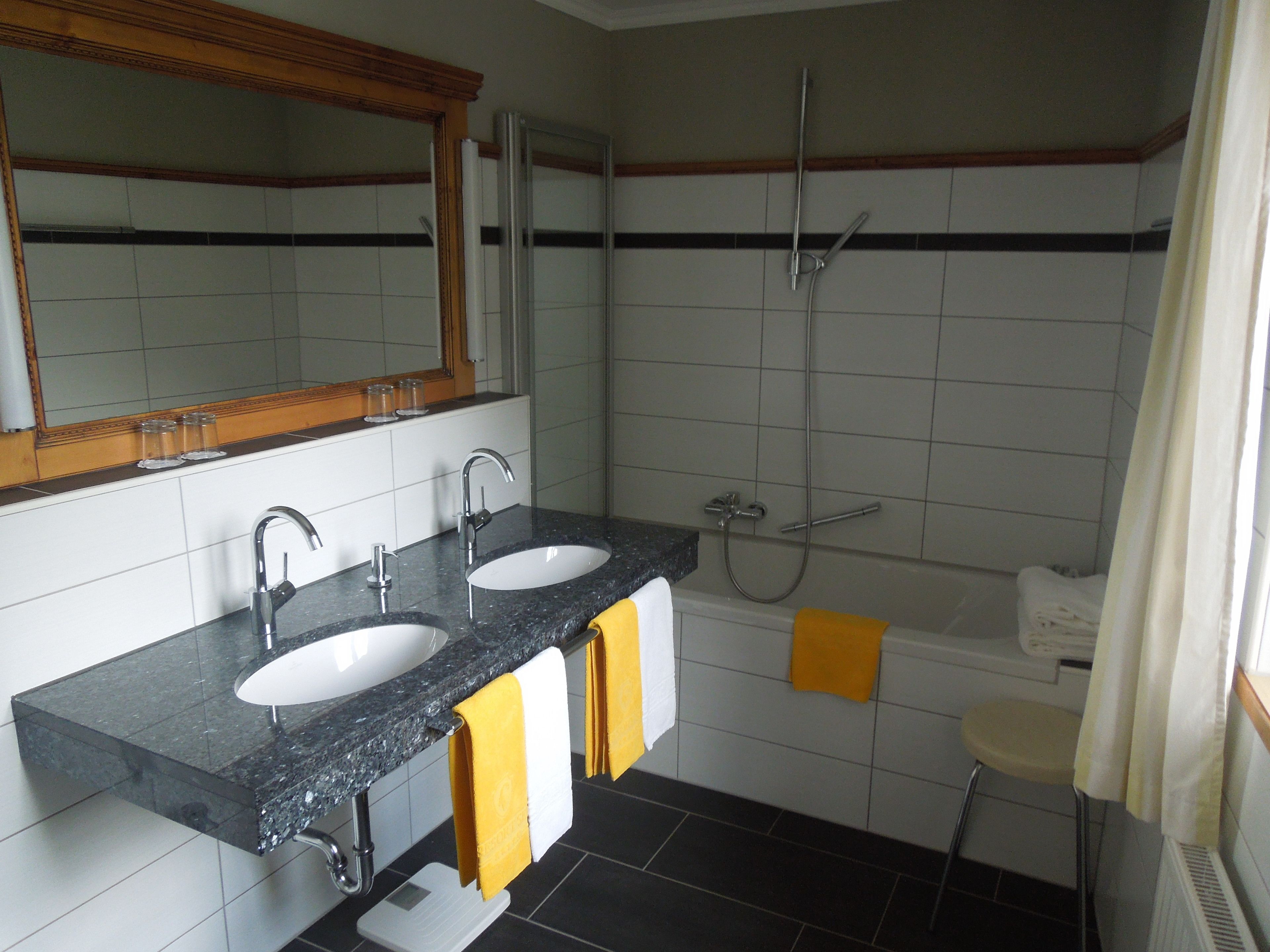 A bathroom with two sinks, a shower, and a toilet.