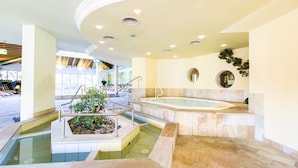Un espacio de spa con un jacuzzi, una piscina pequeña y una escalera que lleva a un nivel superior.