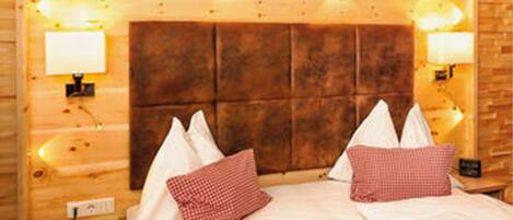 Una habitación de estilo cabaña de madera con una cama grande, dos lámparas de noche y un cabecero de madera.