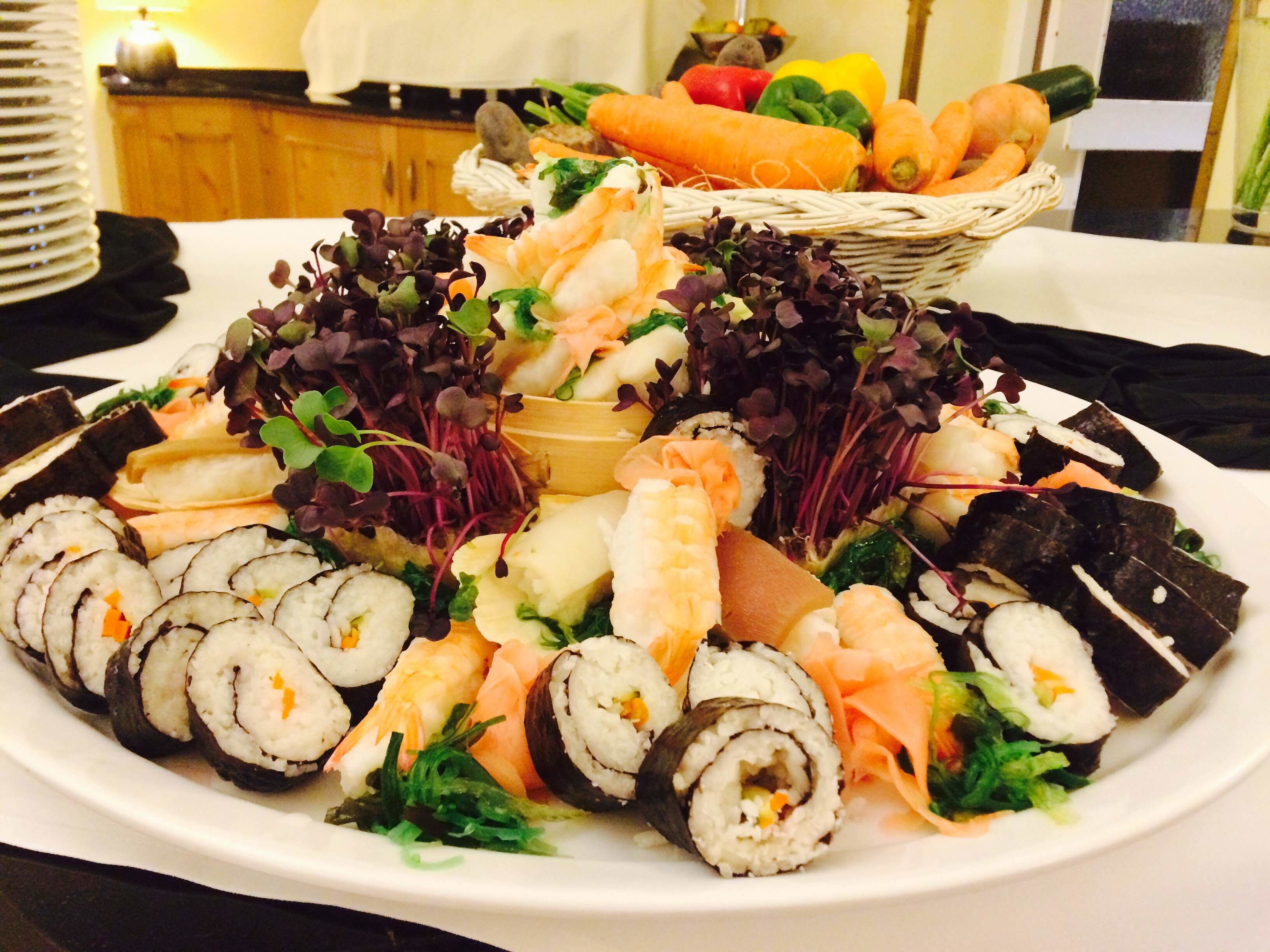 A plate of sushi with various toppings and a basket of vegetables in the background.