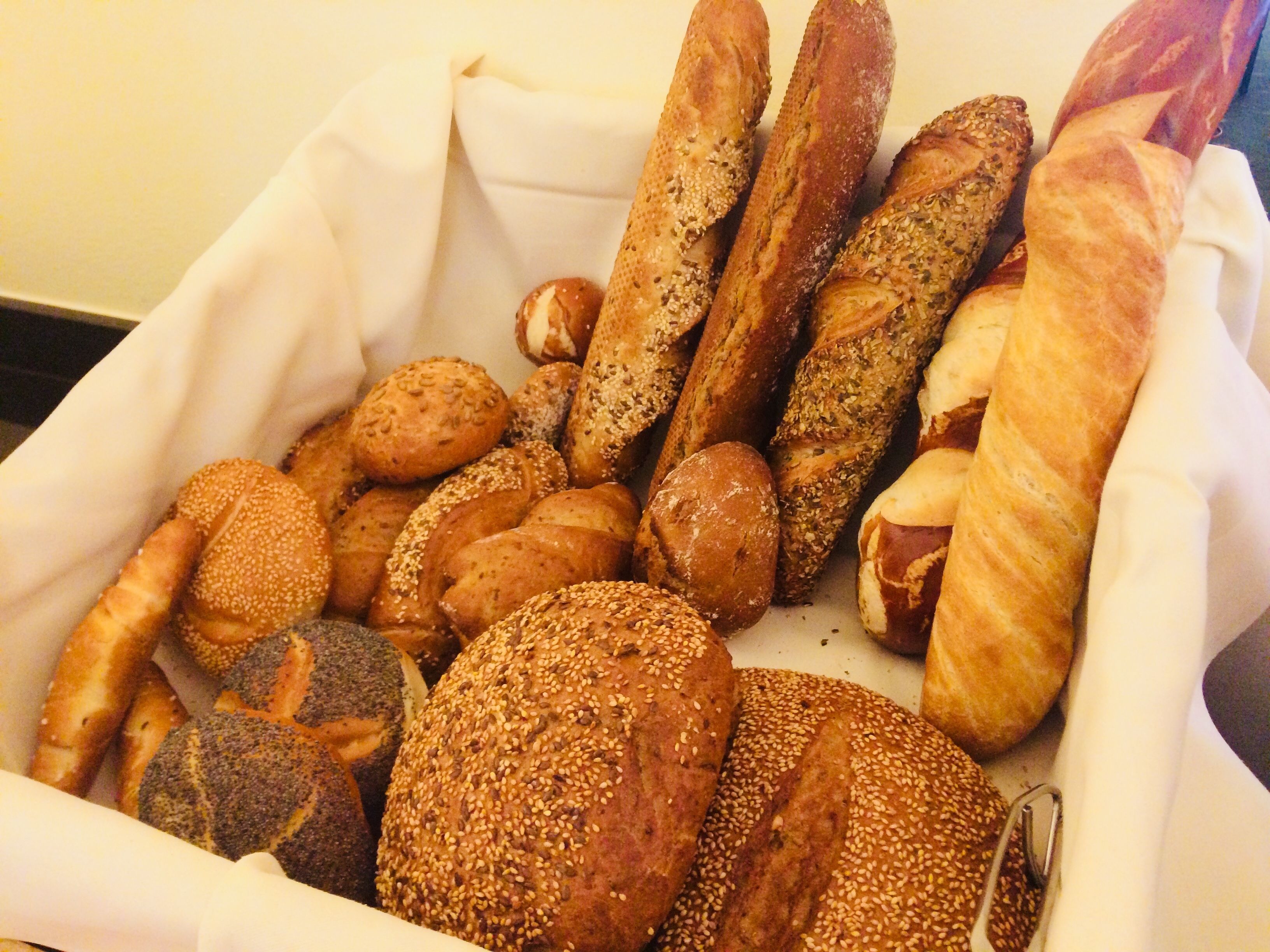 Eine Auswahl an Brot und Brötchen in einem weißen Korb.
