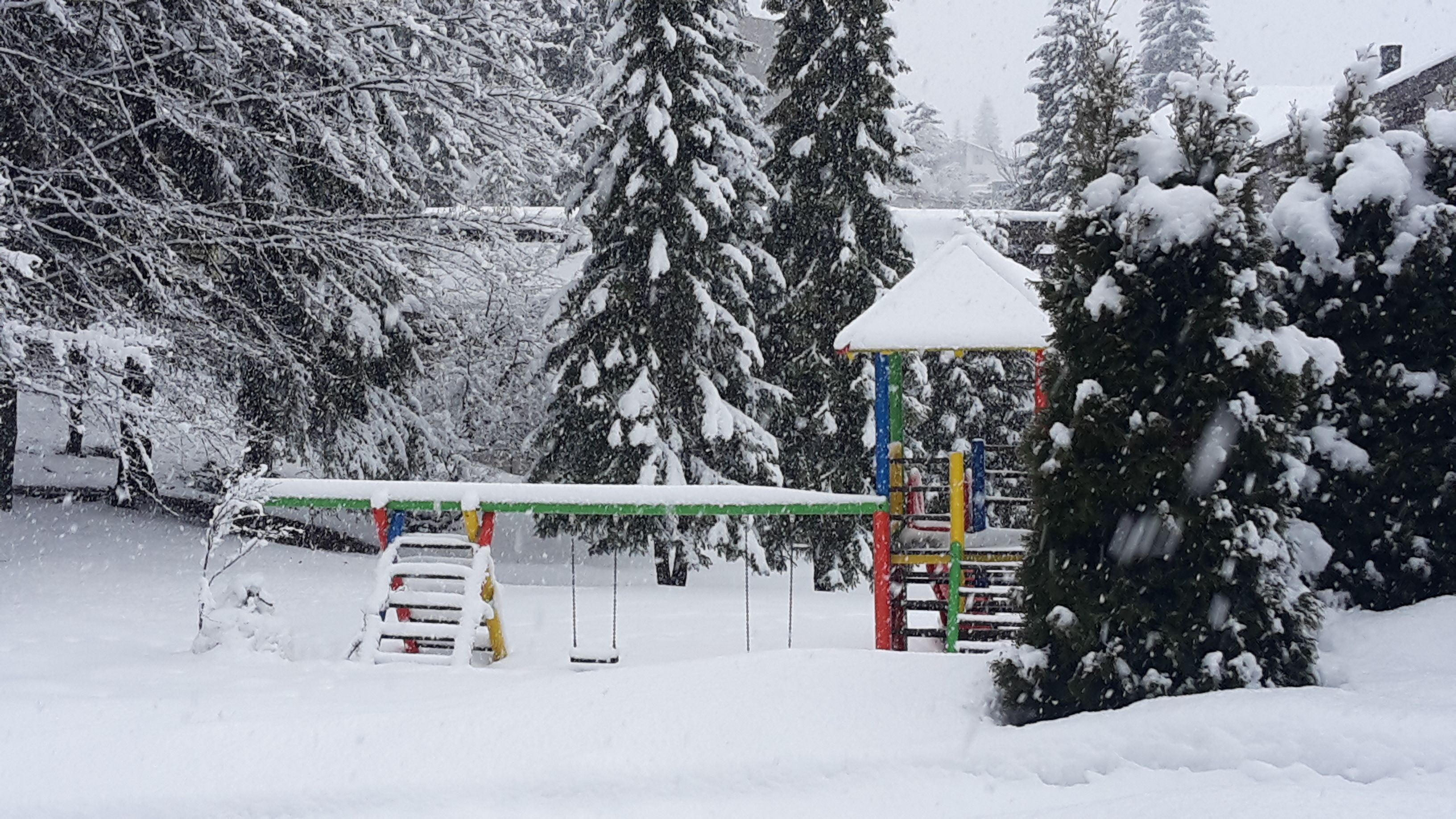 Un parque infantil cubierto de nieve con una estructura de escalada y columpios.