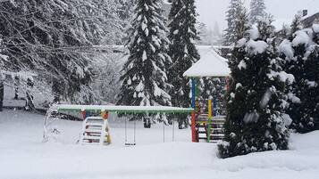 Un parque infantil cubierto de nieve con una estructura de escalada y columpios.