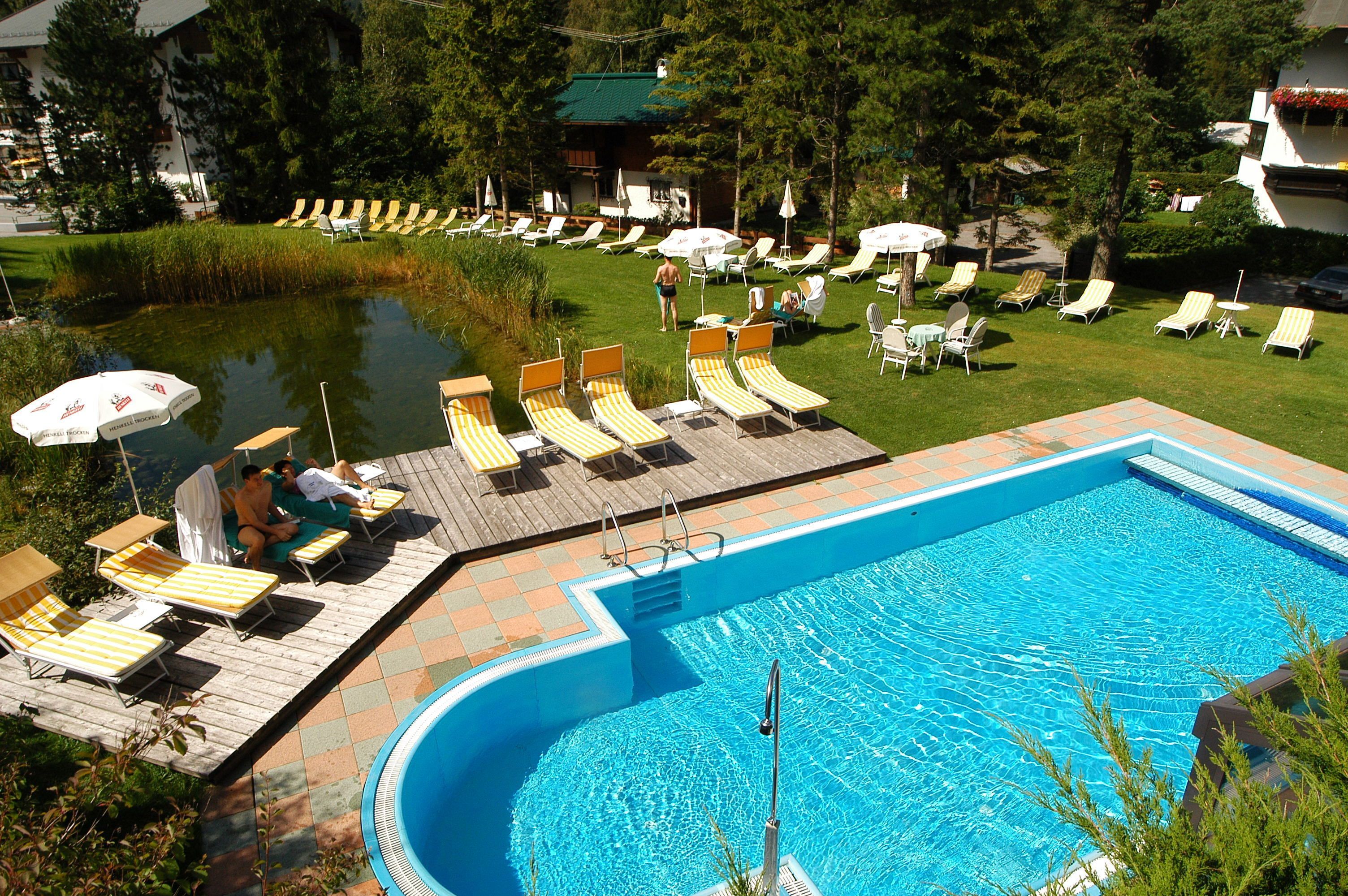 Een buitenzwembad, parasols bij het zwembad en ligstoelen