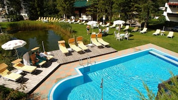 Een buitenzwembad, parasols bij het zwembad en ligstoelen