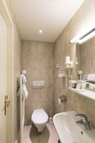 Uma casa de banho moderna com sanita, lavatório e porta-toalhas.