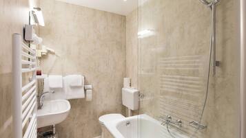 A modern bathroom with a glass-enclosed shower, a standalone bathtub, a sink, and a toilet.