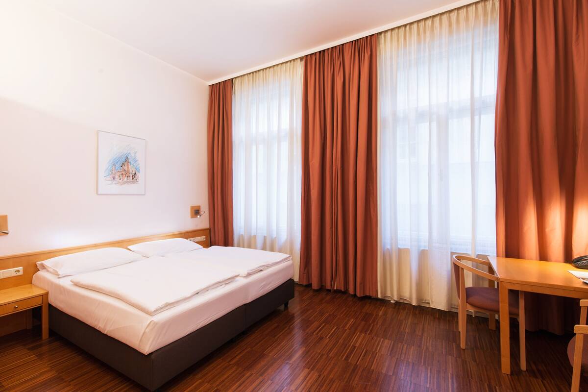 Ein Hotelzimmer mit Bett, Schreibtisch und Stuhl.