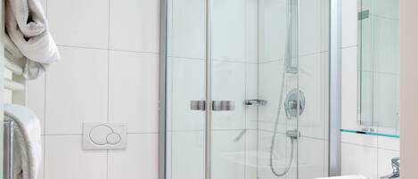 A modern bathroom with a glass-enclosed shower, a white toilet, and a sink with a mirror.