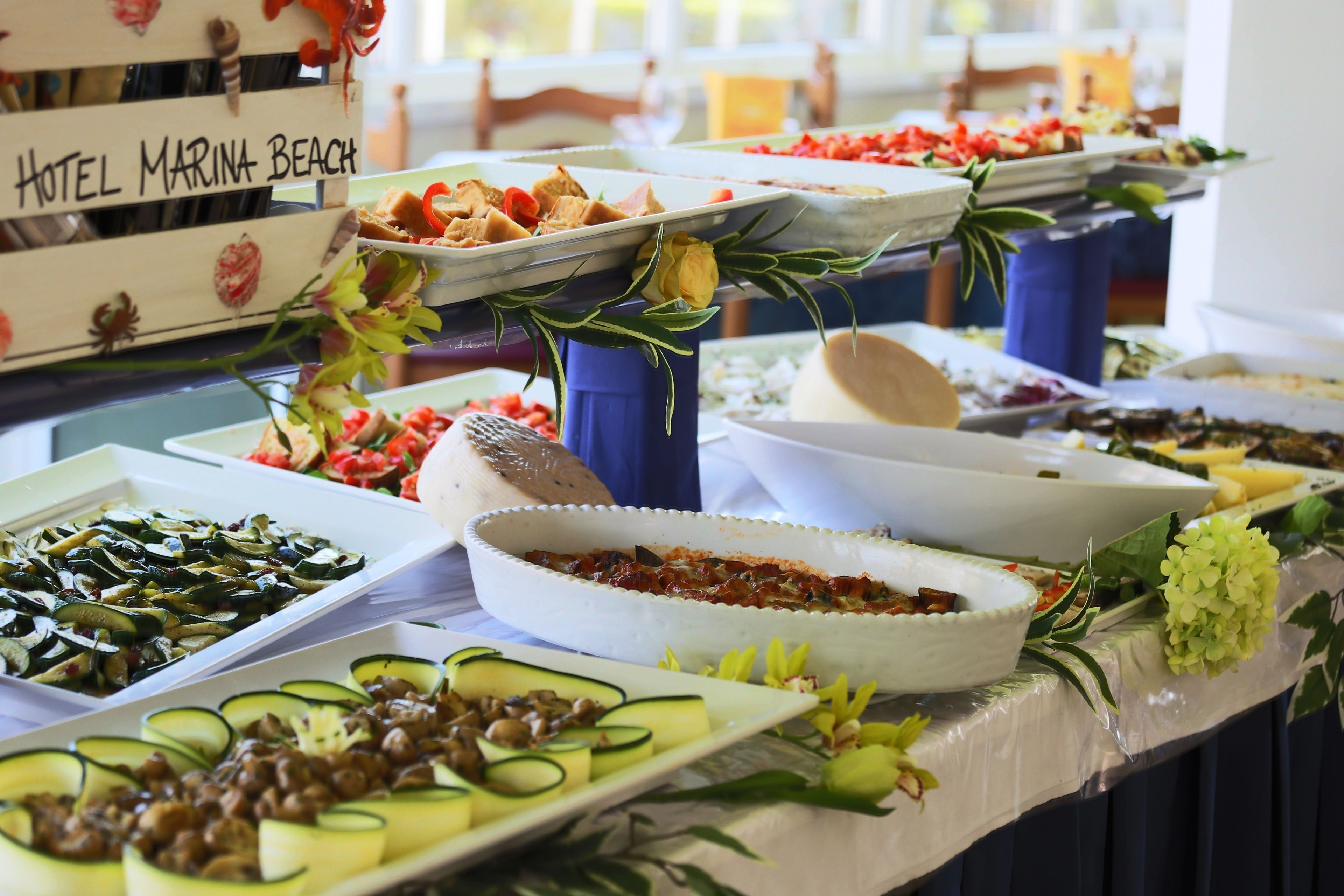 A buffet table with various food items and a sign that reads "Hotel Marina Beach".