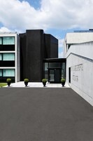 Un edificio moderno con fachada curva, entrada de vidrio y un letrero que dice "The Park Hotel".