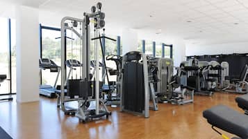 Academia moderna com aparelhos de cardio, estações de musculação e muita luz natural.