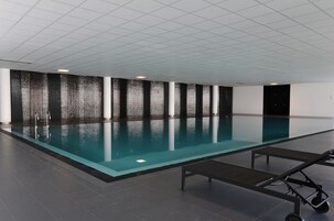 Una amplia piscina cubierta con suelo de baldosas y techo con diseño de cuadrícula.