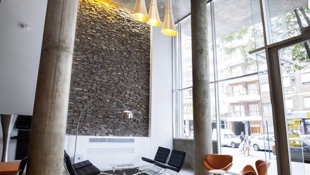 A modern interior with a stone wall, a piano, and seating areas.