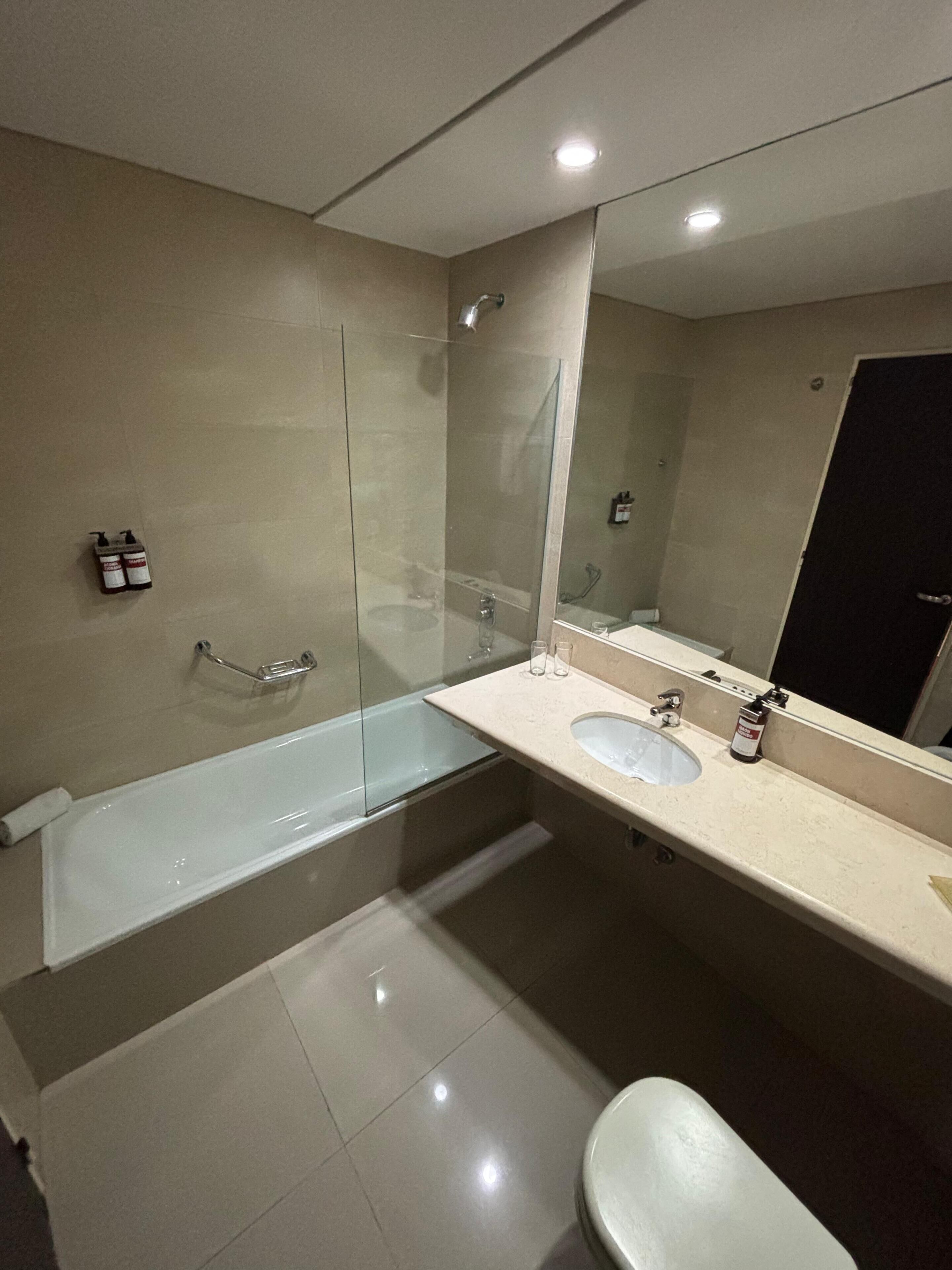 A modern bathroom with a glass-enclosed shower, a bathtub, a sink, and a toilet.