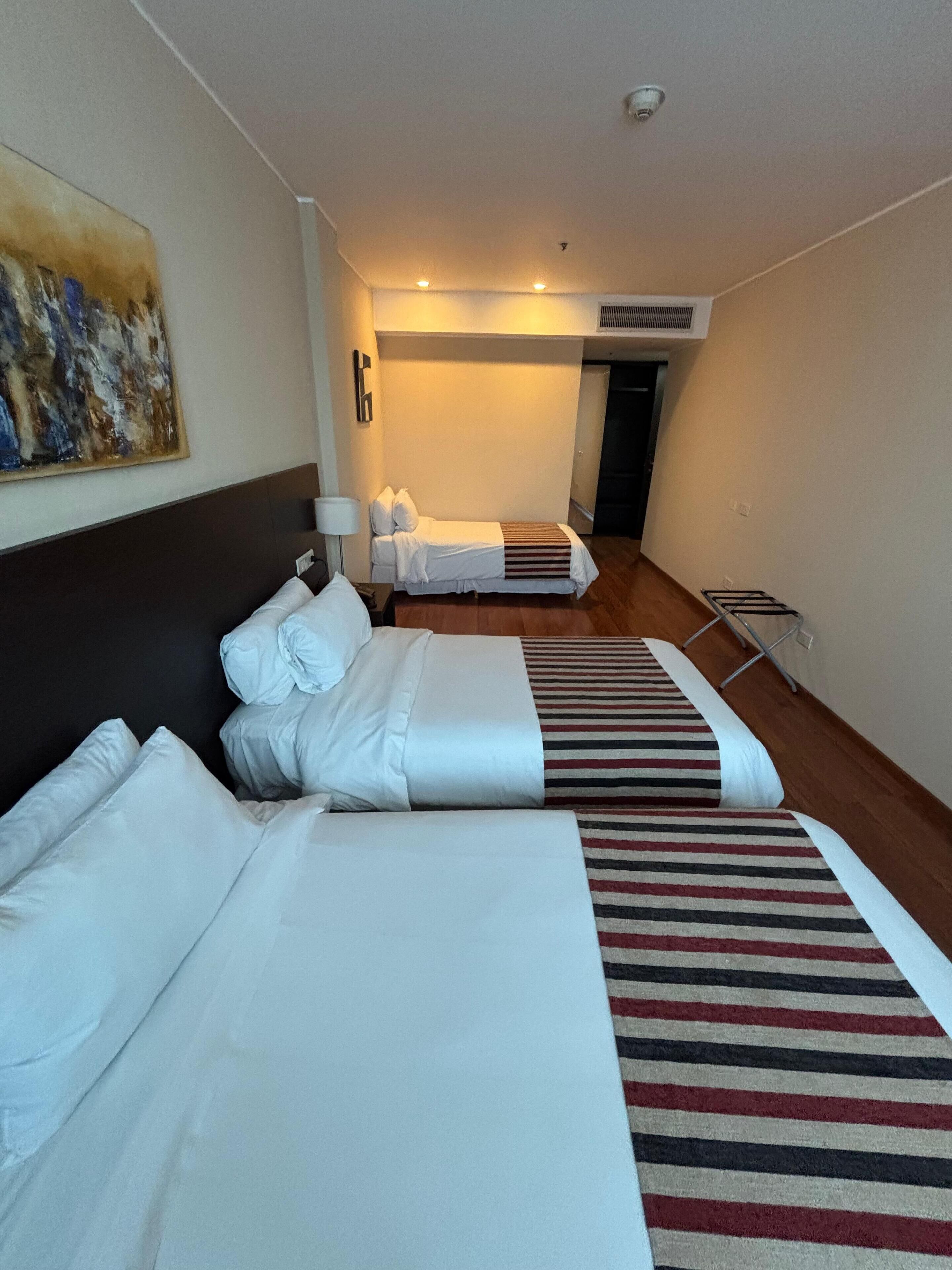 Una habitación de hotel con dos camas, un cuadro en la pared y una cámara de seguridad instalada en el techo.