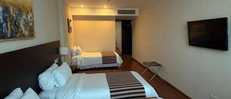 A hotel room with two beds, a TV, and a painting on the wall.