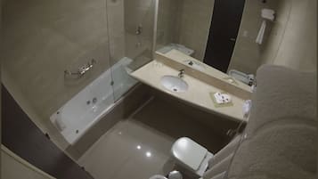 Un baño moderno con ducha envuelta en vidrio, bañera, inodoro, lavabo y tocador con espejo.