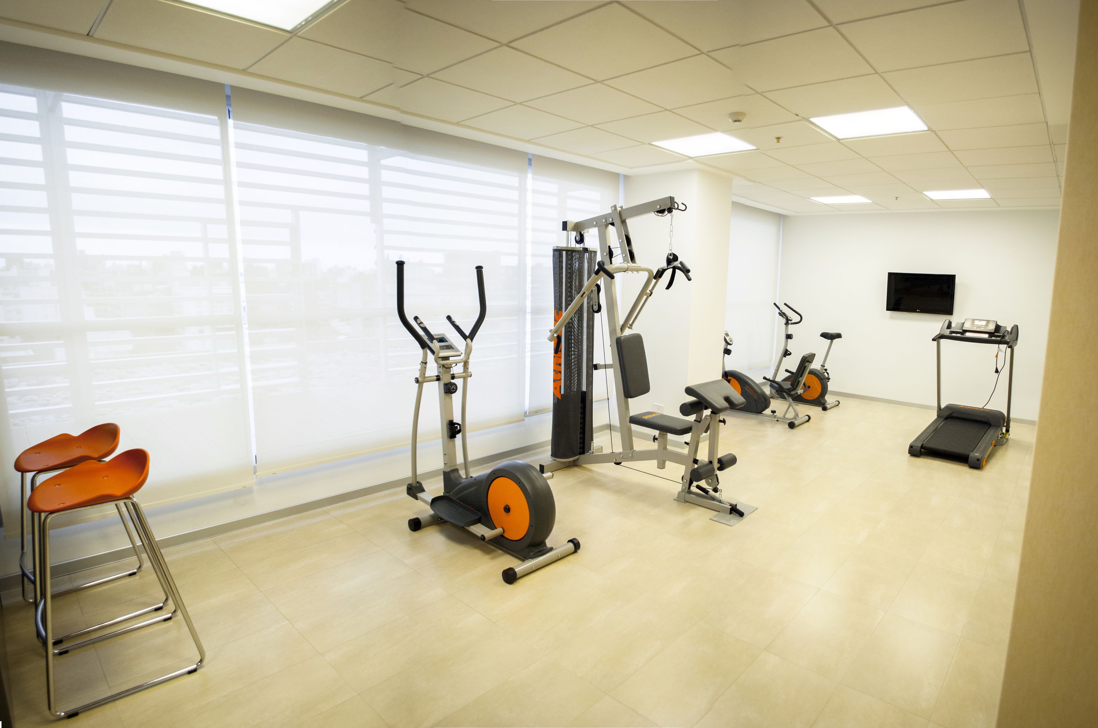 Ett gym med konditionsmaskiner, styrketräningsutrustning och ett löpband.