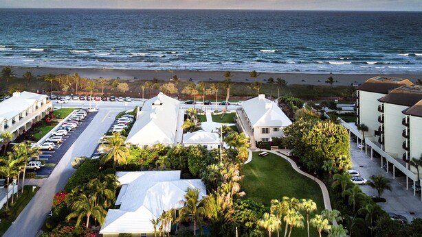 A resort with a pool, palm trees, and a view of the ocean. - Getaways At Dover House (Delray Beach)