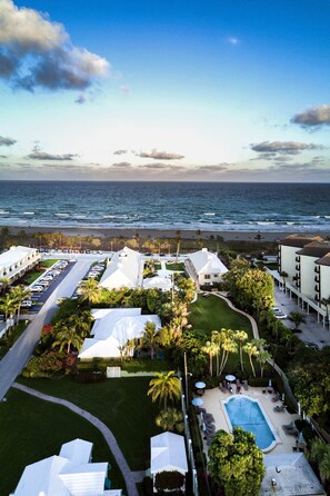 Een resort met een zwembad, palmbomen en uitzicht op de oceaan.
