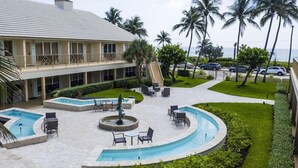 A resort with a pool area, outdoor seating, palm trees, and a view of the ocean. - Getaways At Dover House (Delray Beach)
