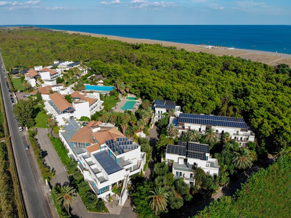 Zona residencial costera con casas modernas que incluyen paneles solares, piscina y abundante vegetación.