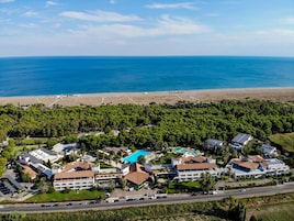 An aerial view of a coastal resort with multiple buildings, a swimming pool, and a beach.