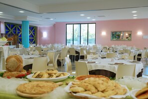 A dining area with multiple tables set for a meal, featuring a variety of dishes and bread. - Club Giardini d'Oriente Village (Nova Siri)