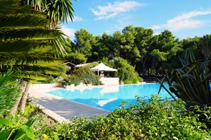 A clear blue pool surrounded by lush greenery and a gazebo. - Club Giardini d'Oriente Village (Nova Siri)