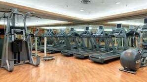 A gym with multiple treadmills, elliptical machines, and a large exercise ball.