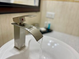Un baño moderno con un grifo de acero inoxidable y un lavamanos blanco.