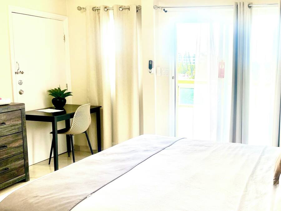 Ein Hotelzimmer mit einem Bett, einem Schreibtisch, einem Stuhl und einer Topfpflanze.