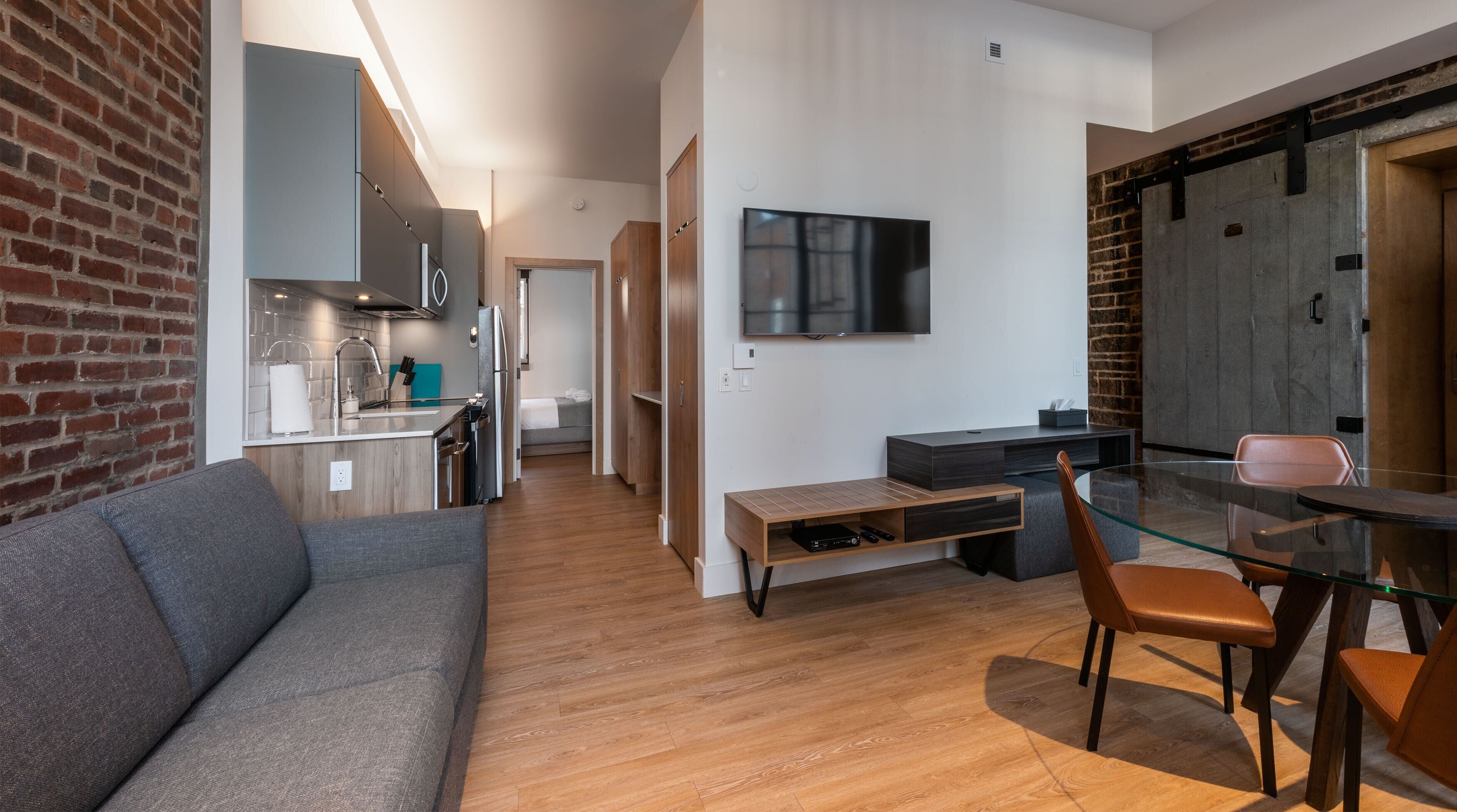 A modern living space with a kitchen, dining area, and a TV mounted on the wall.