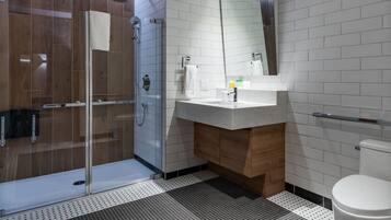 A modern bathroom with a glass shower enclosure, a white sink with a mirror above it, and a toilet.