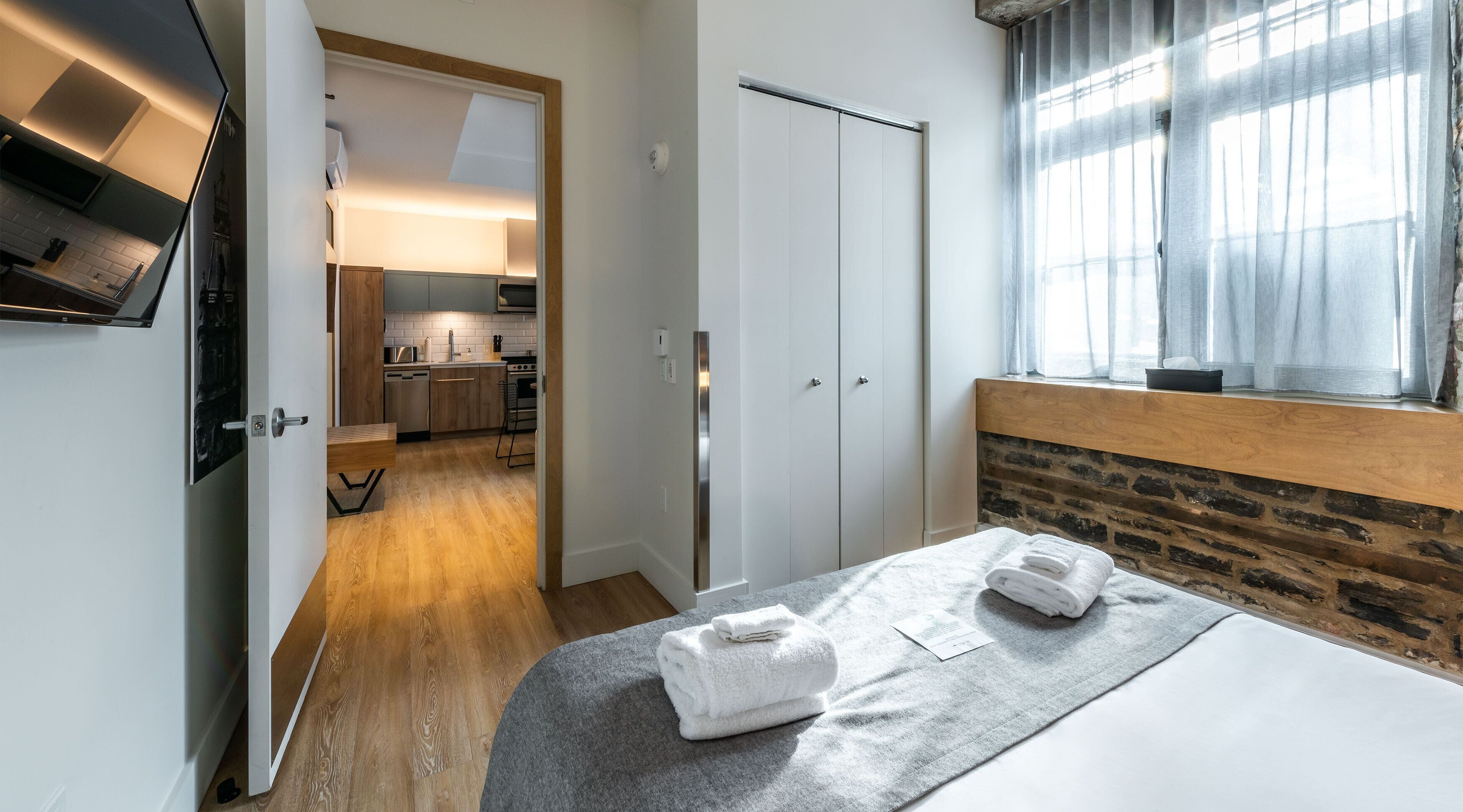 Una habitación de hotel con cama, baño, zona de cocina y vistas al exterior.