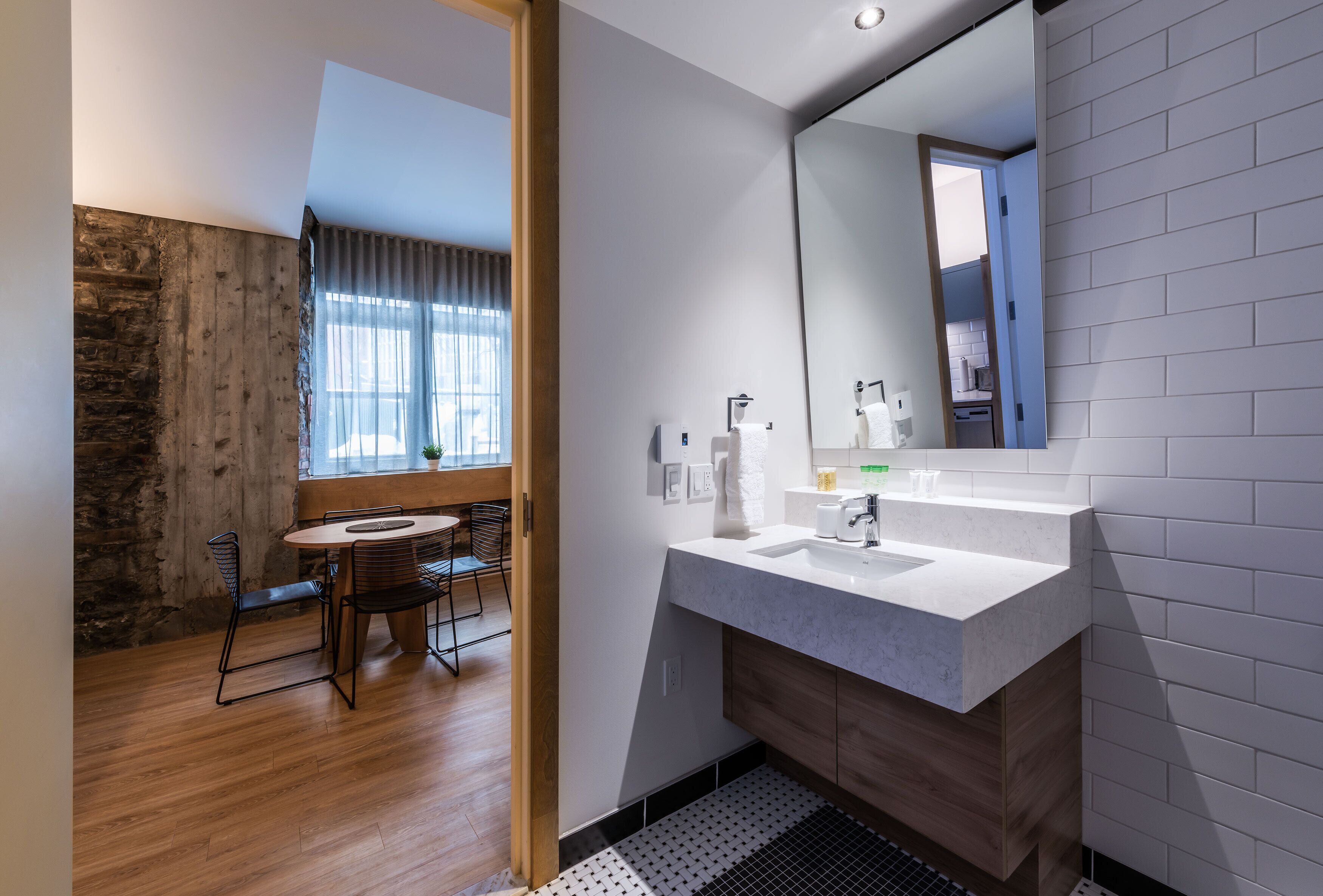 A modern bathroom with a large mirror, two sinks, and a wooden vanity.