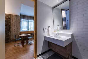 A modern bathroom with a large mirror, two sinks, and a wooden vanity.