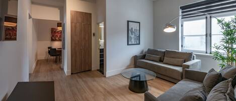 Una sala de estar moderna con un sofá, una mesa de centro de vidrio y un comedor con sillas y una mesa.