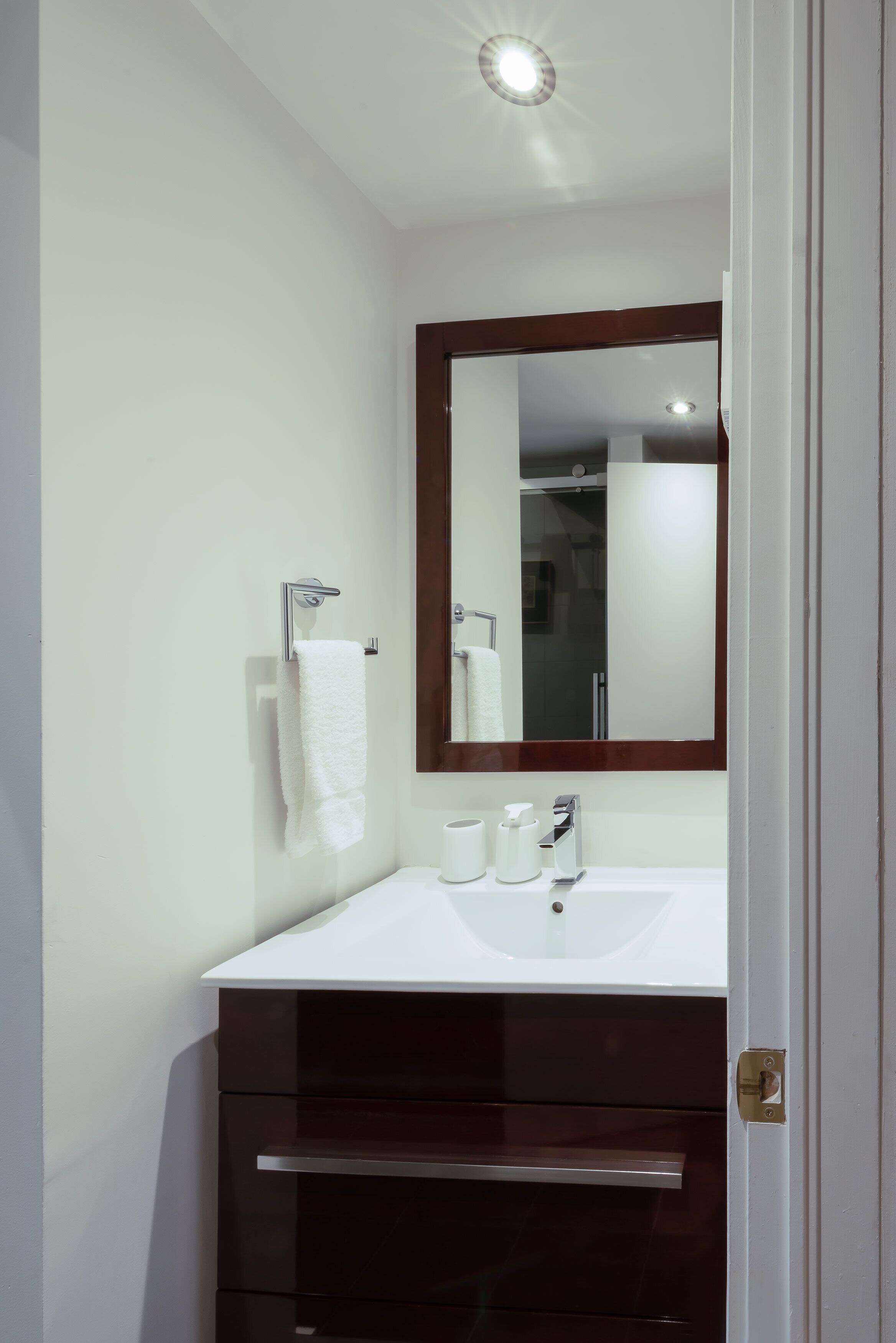 A bathroom with a white sink, a mirror, and a towel hanging on the wall.
