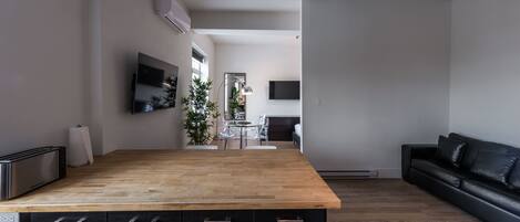 A modern kitchen with a wooden countertop, black cabinets, and a dining area with a table and chairs.