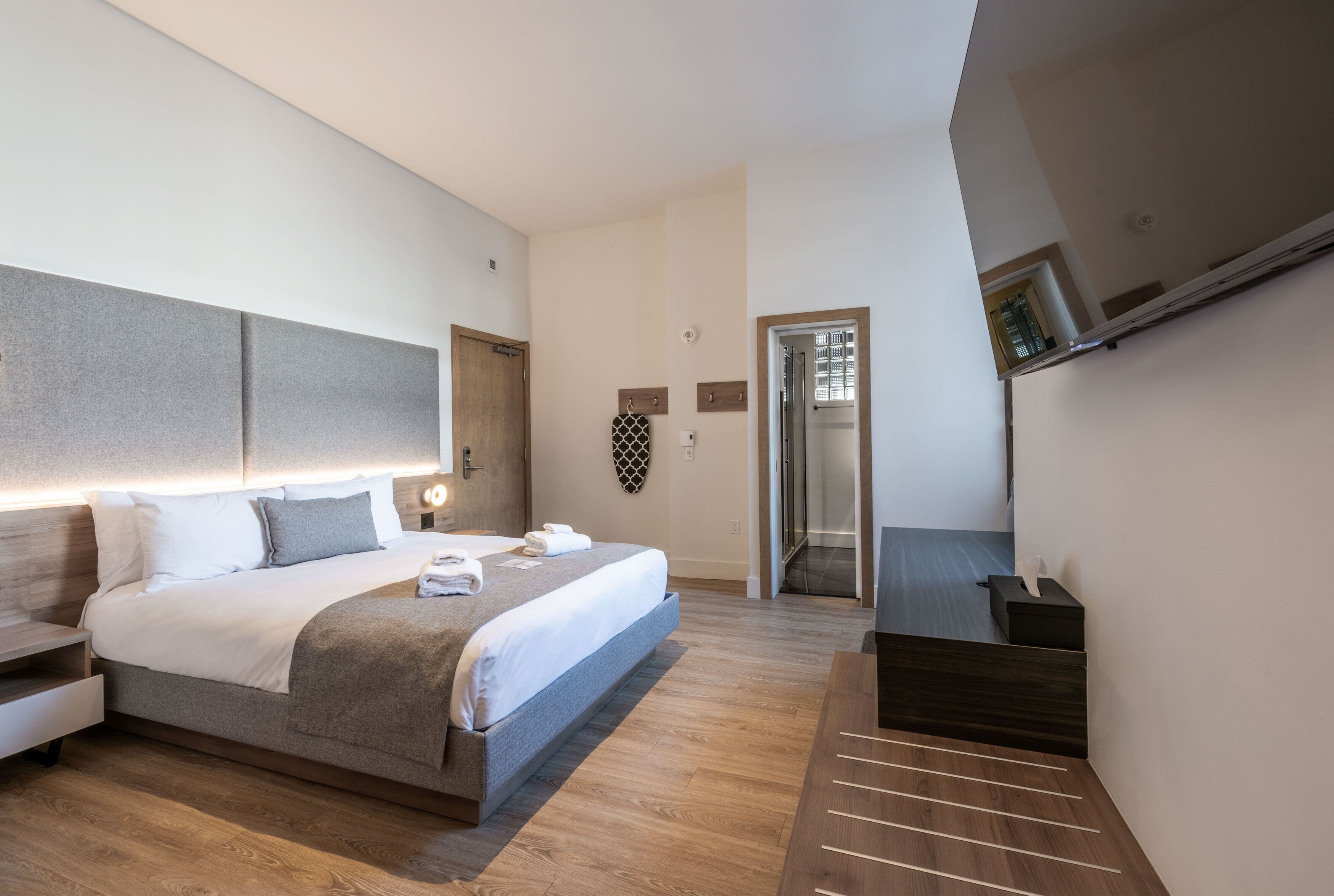 Un dormitorio moderno con una cama grande, mesitas de noche, televisor integrado y vestidor.