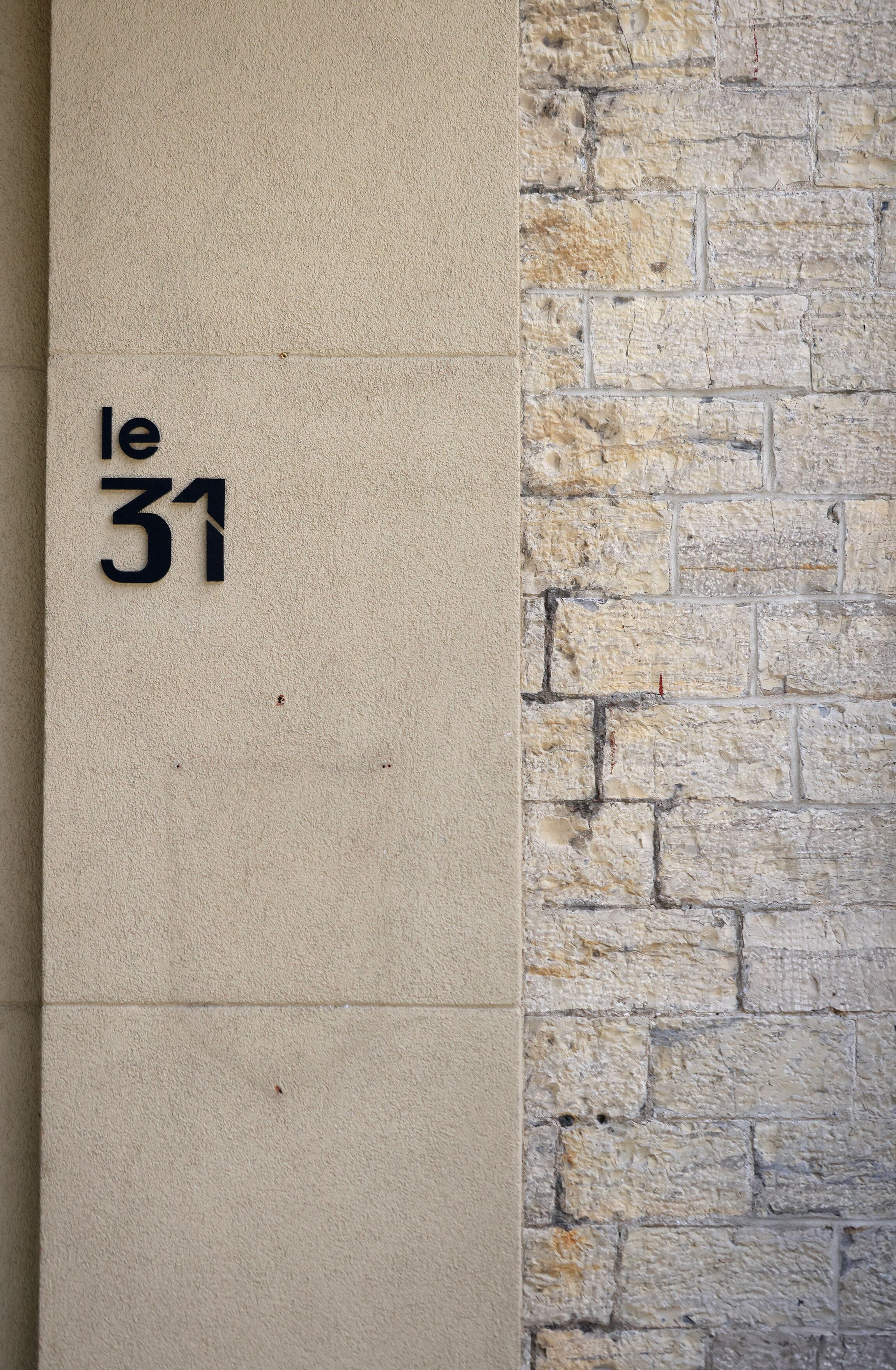 A wall with a beige textured surface and a stone wall section. The number "31" is visible on the beige surface.