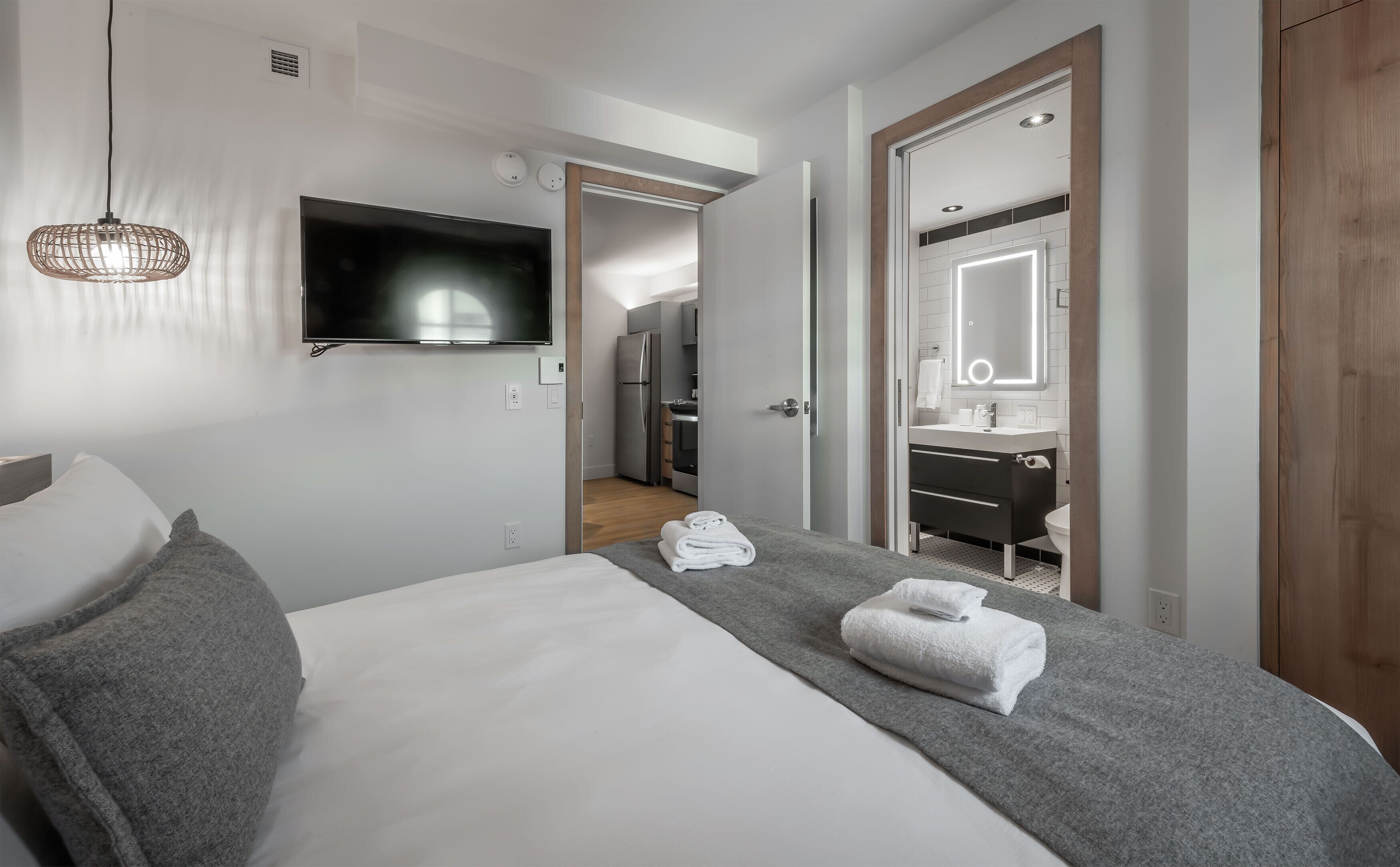 Et moderne hotelværelse med seng, fjernsyn, badeværelse med spejl og tekøkken.