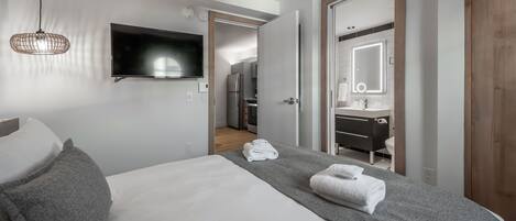 Et moderne hotelværelse med seng, fjernsyn, badeværelse med spejl og tekøkken.