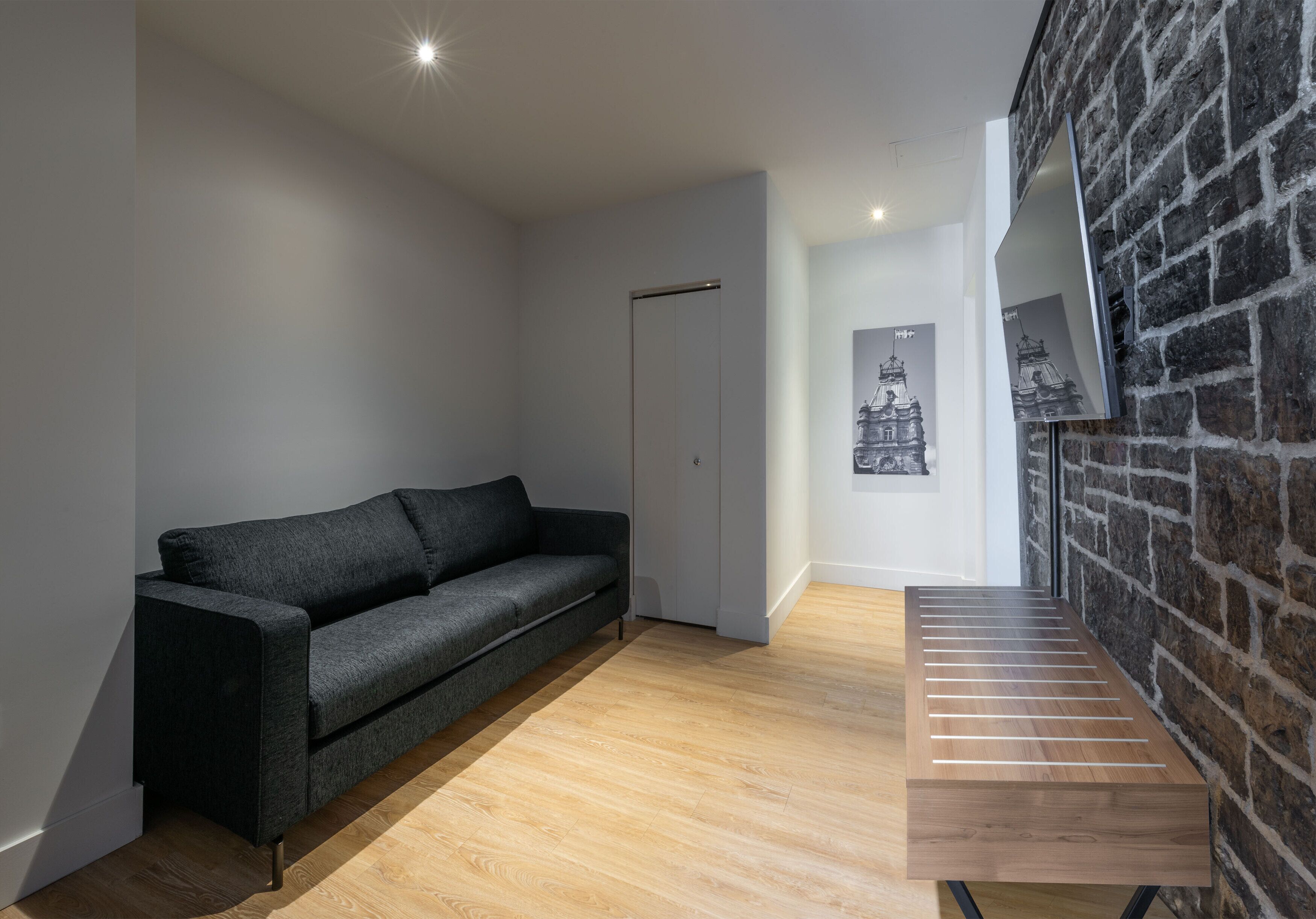 Ein modernes Interieur mit einem dunkelgrauen Sofa, einer Holzbank und einer Ziegelwand.